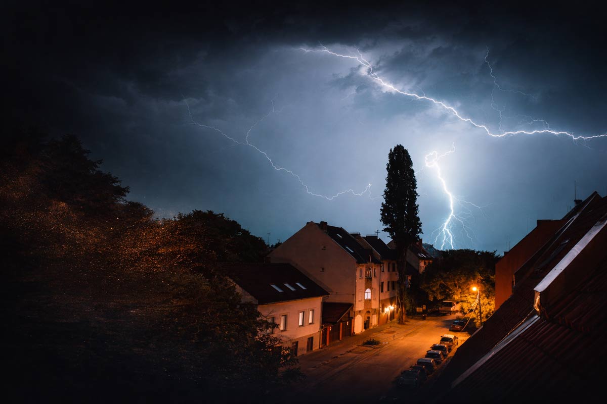 Haus bei Gewitter mit Blitz als Symbol für Überspannungsschutz im Haus